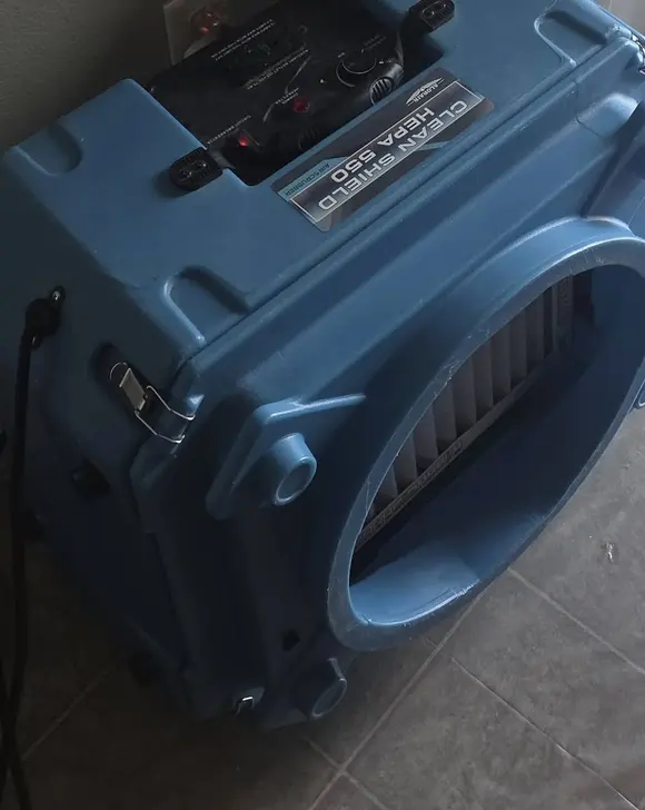 A blue air scrubber beside a plastic containment wall